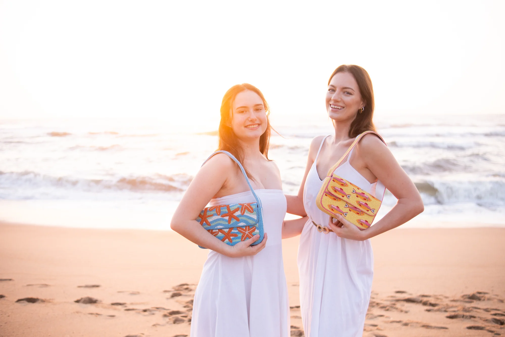 Two friends wearing colourful beaded bags on the beach